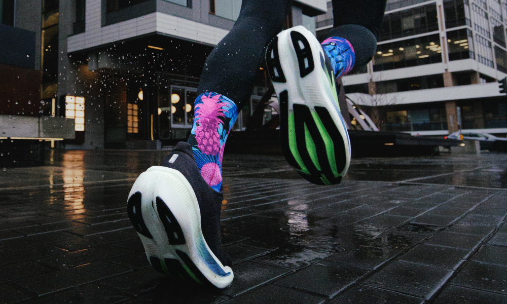 Runner in motion on wet pavement wearing OUTWAY athletic crew socks with tropical pineapple pattern