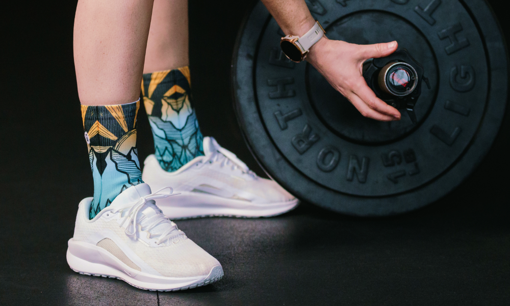Person at the gym wearing OUTWAY athletic crew socks with geometric mountain pattern next to a weight plate