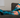 Person resting on a couch wearing OUTWAY teal knee-high compression socks with tree and sunset pattern