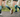 Two runners on an outdoor trail wearing OUTWAY knee-high compression socks with a teal forest tree design, shot from behind at ground level showing legs mid-stride.