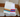 Two pairs of OUTWAY athletic crew socks with colourful stripe designs draped over a wooden chair arm